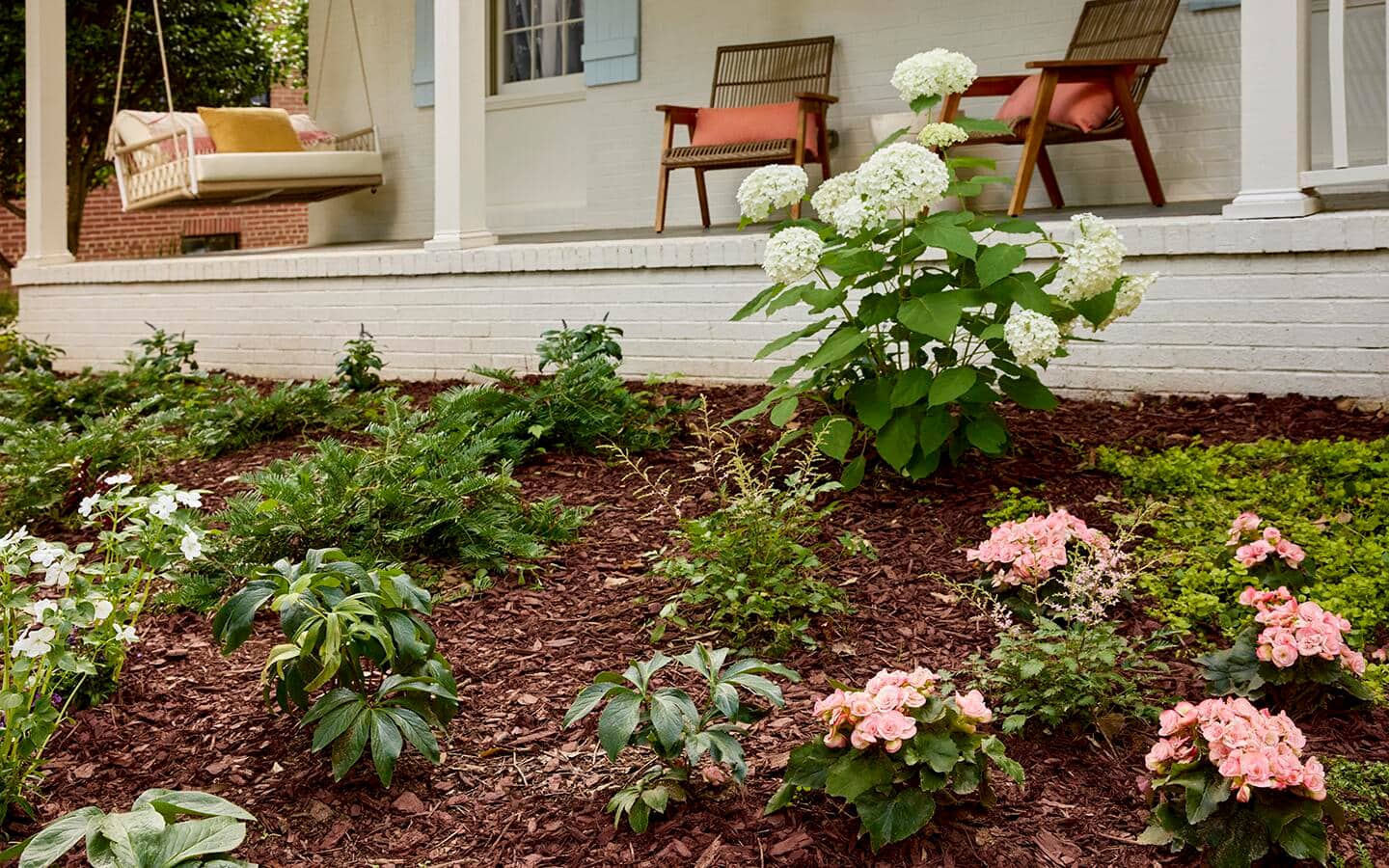 Brown pine mulch placed around plants in a garden in front of a backyard porch. Brown pine mulch placed around plants in a garden in front of a backyard porch.