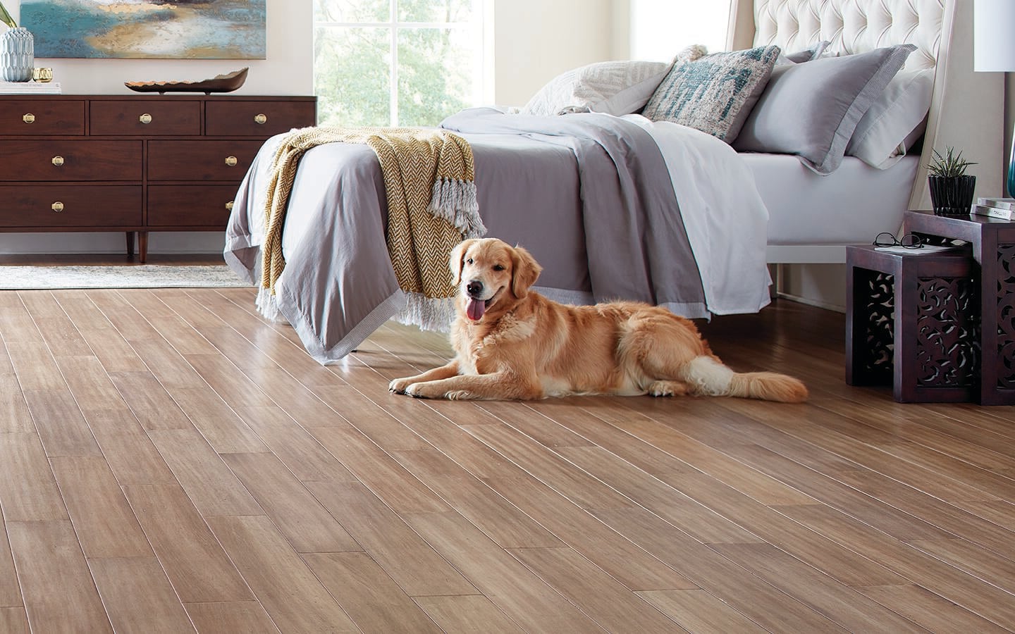 A dog lays on laminate flooring in a bedroom.
