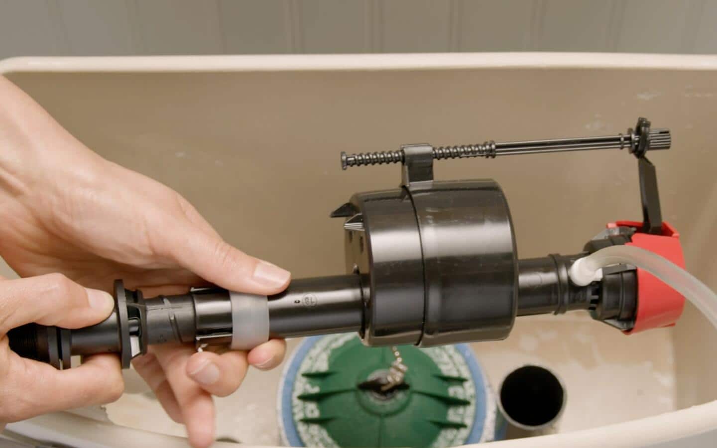 A person inserting a new fill valve in a toilet tank. A person inserting a new fill valve in a toilet tank.