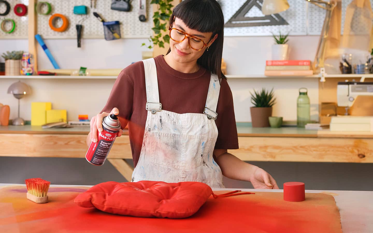 A person spray painting a pillow cushion from outdoor furniture.