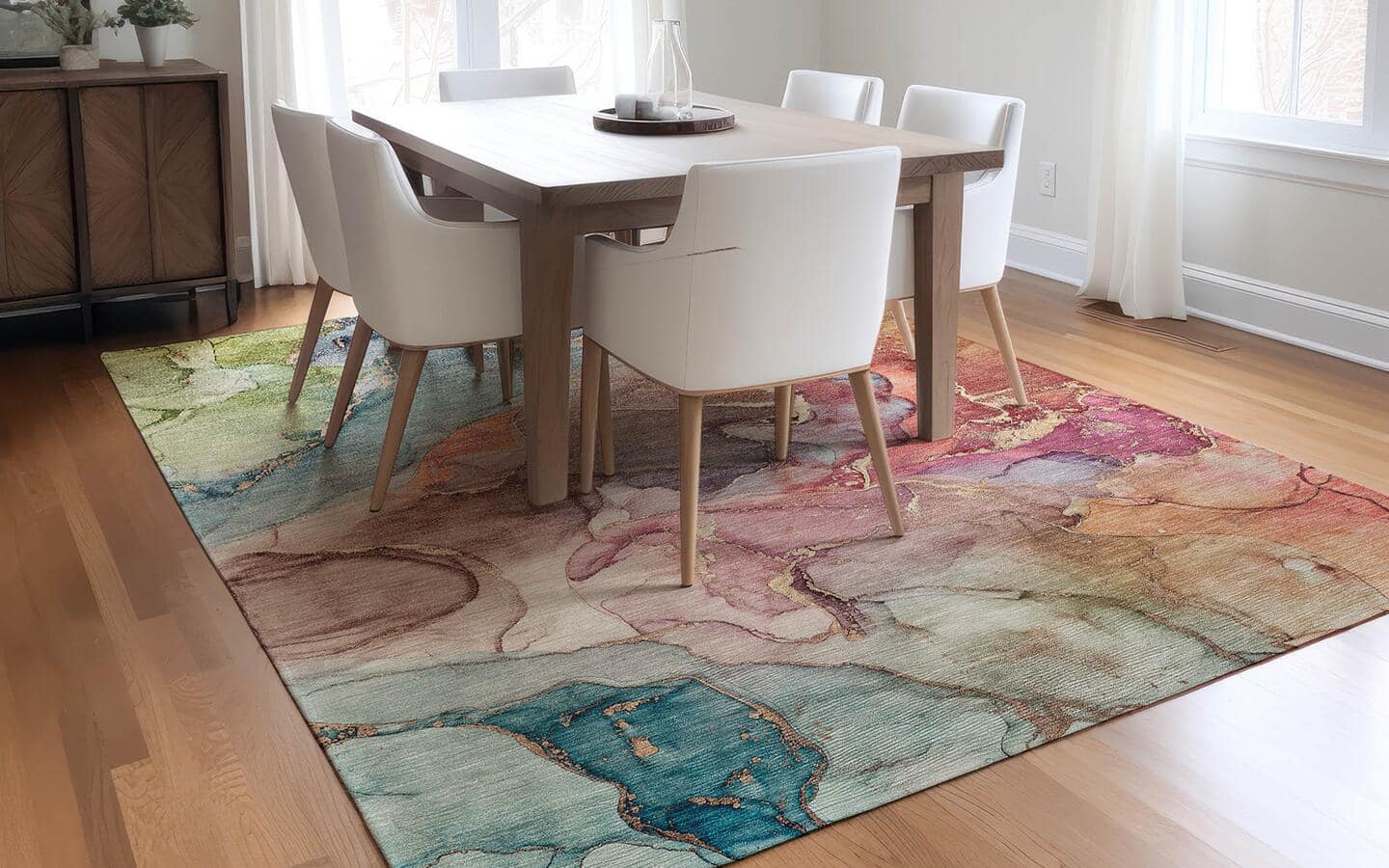 A watercolor rug lays underneath a small, white dining room set.