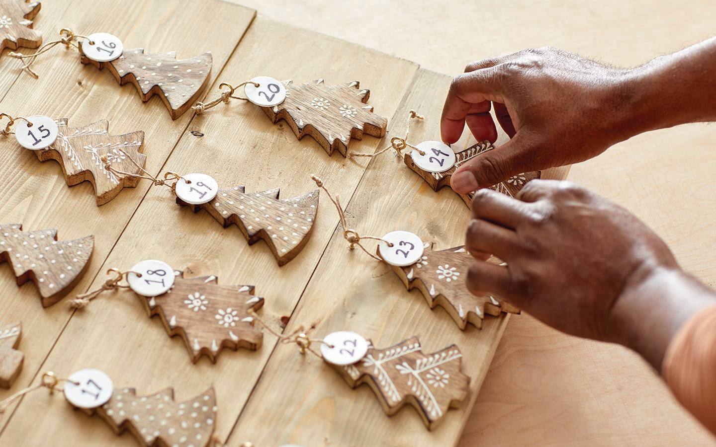 Someone completing a wood Advent calendar with all the dates neatly hung.