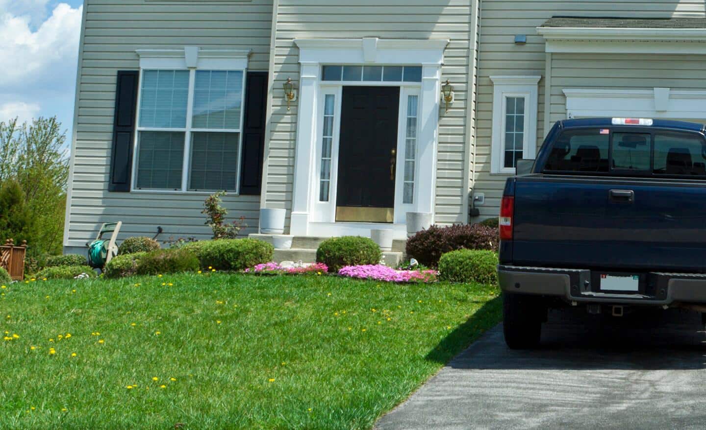 A truck parked on a paved driveway in front of a house.