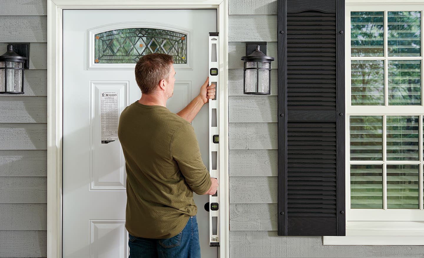 A man using a level on the frame of a home entryway.