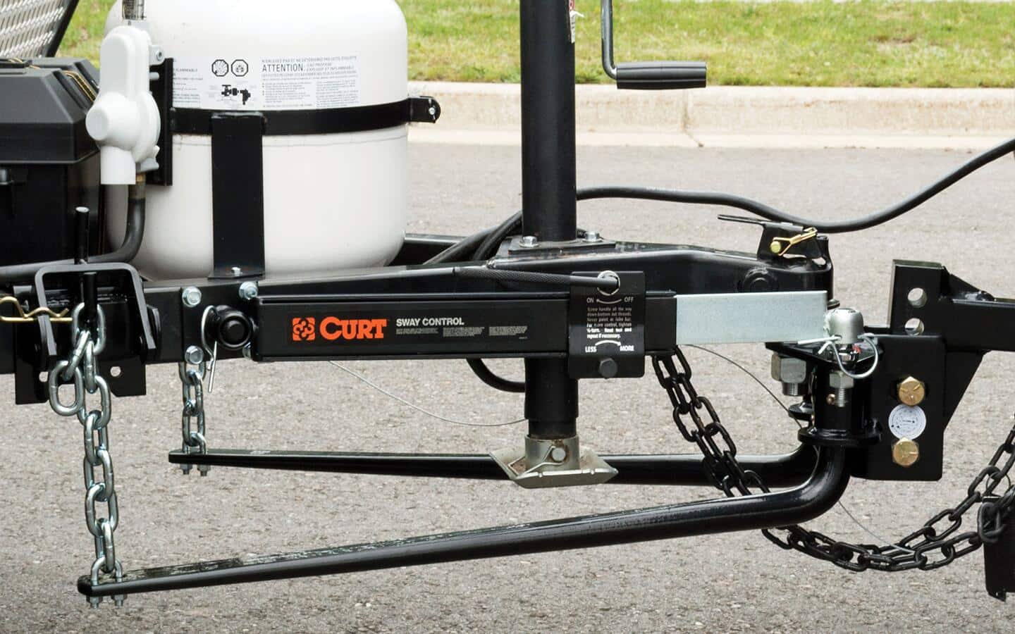 A black weight distribution hitch connects a tow vehicle to a trailer.