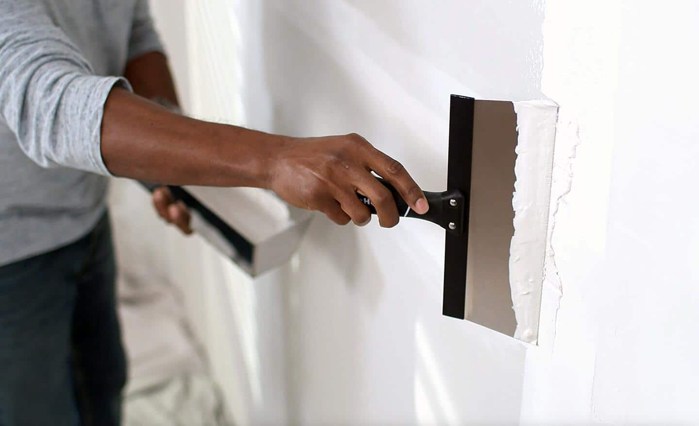 Someone applying a second coat of drywall mud to a joint.