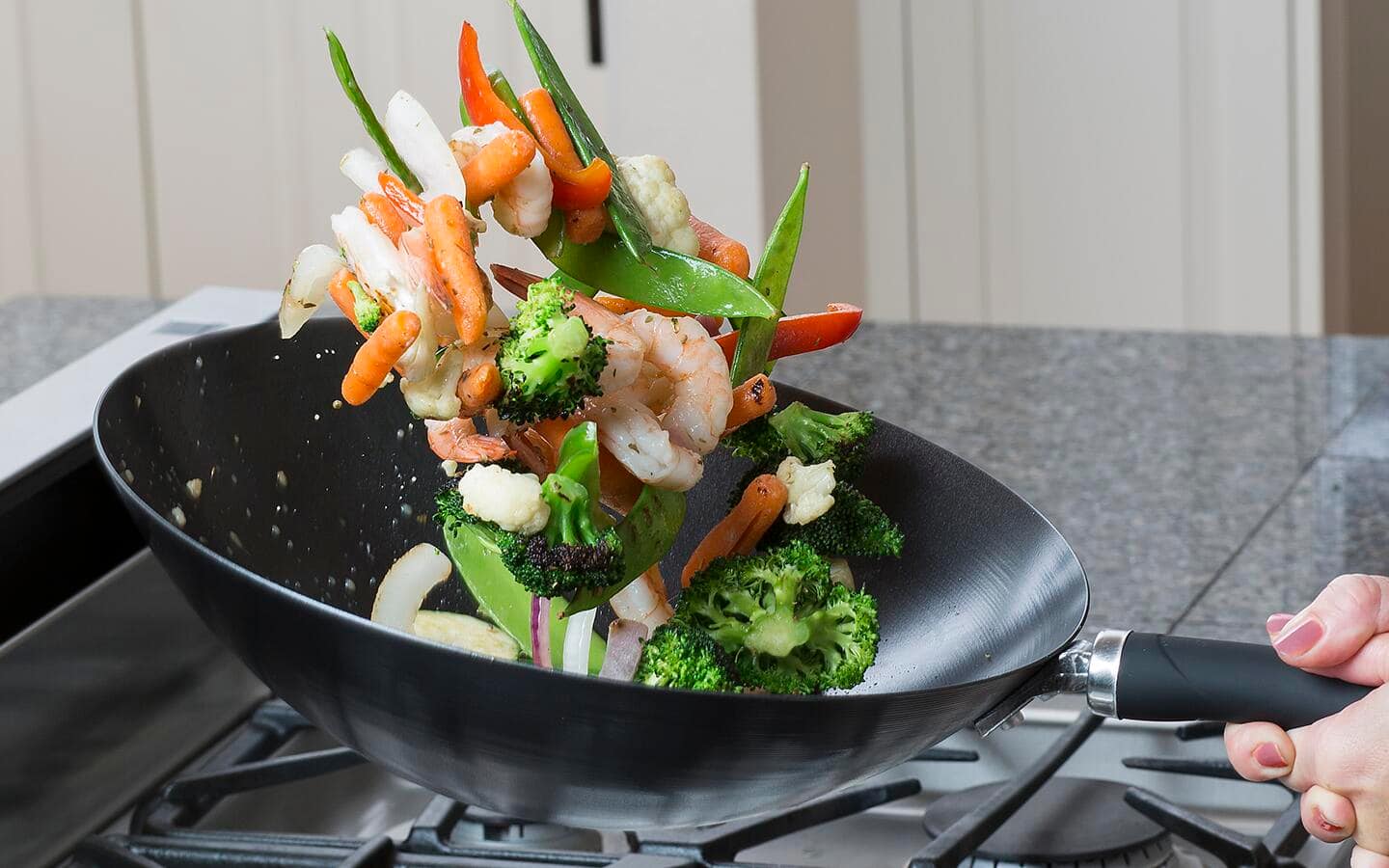 Shrimp and colorful vegetables being flipped in an aluminum wok. Shrimp and colorful vegetables being flipped in an aluminum wok.