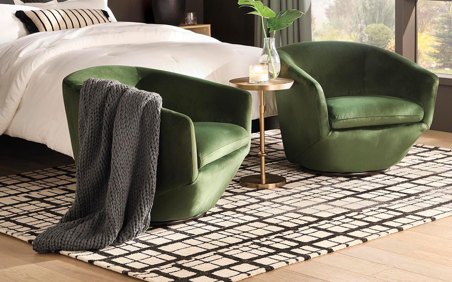 A rug with a black and white geometric pattern lays at the foot of a bed.