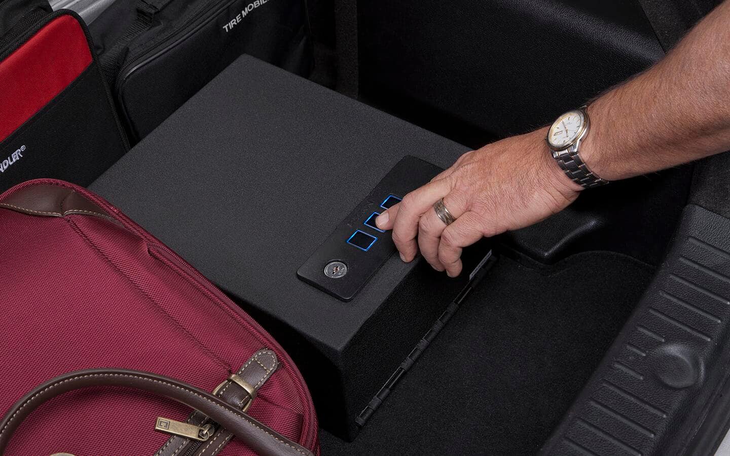 A person opening a quick access safe next to a red bag.