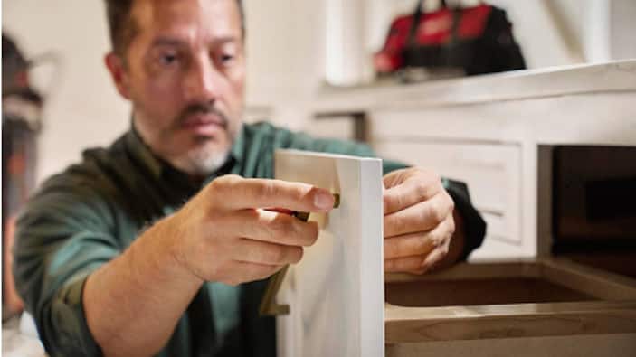 A remodeler installs new kitchen cabinets.