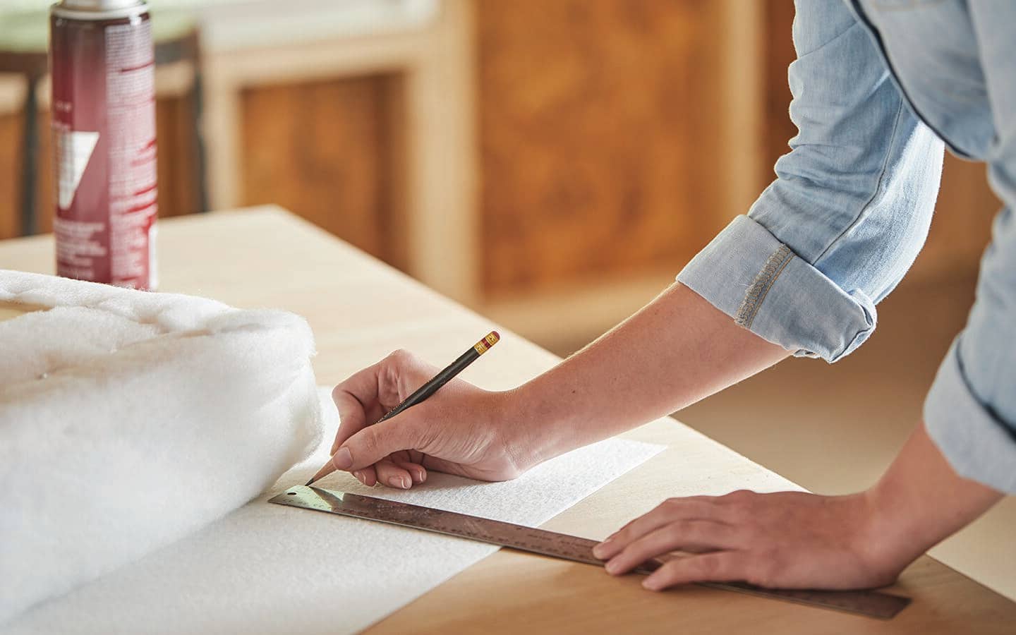A person measures fabric to trim for a storage ottoman. A person measures fabric to trim for a storage ottoman.