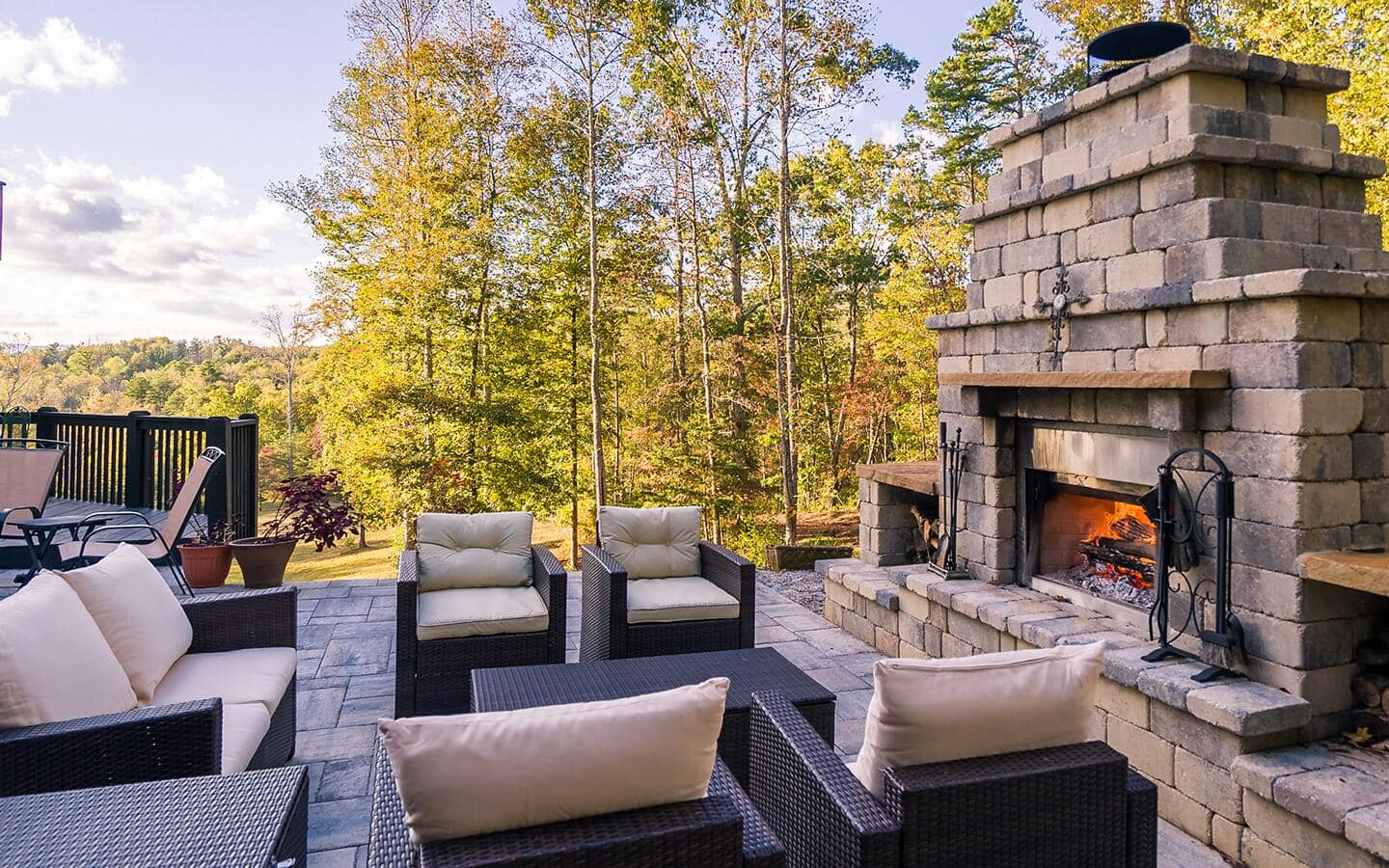 A stone outdoor fireplace surrounded by comfortable patio furniture.