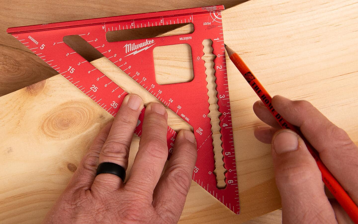 A person using a rafter square to mark an angle. A person using a rafter square to mark an angle.