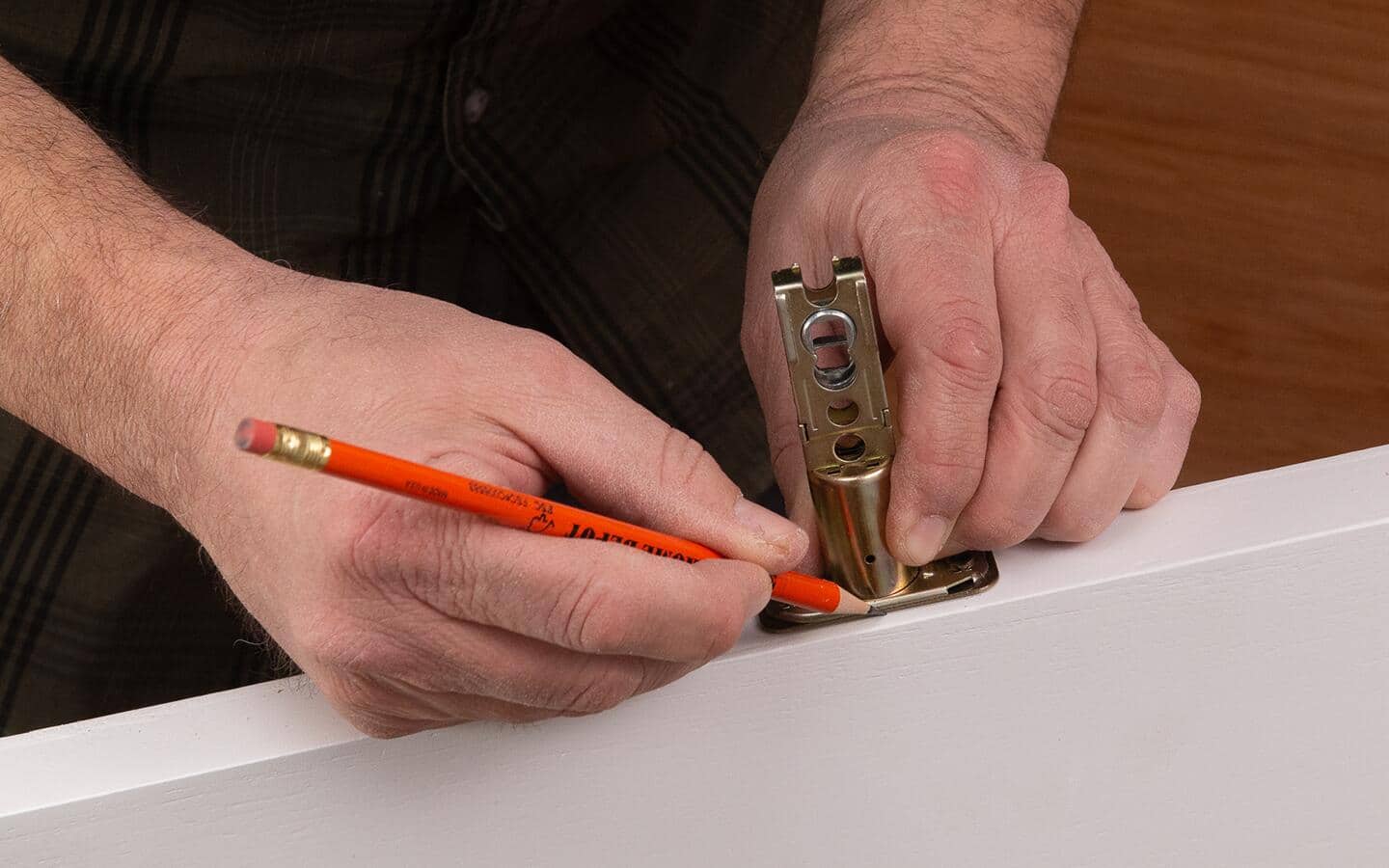 A person marks a latch mortise. A person marks a latch mortise.