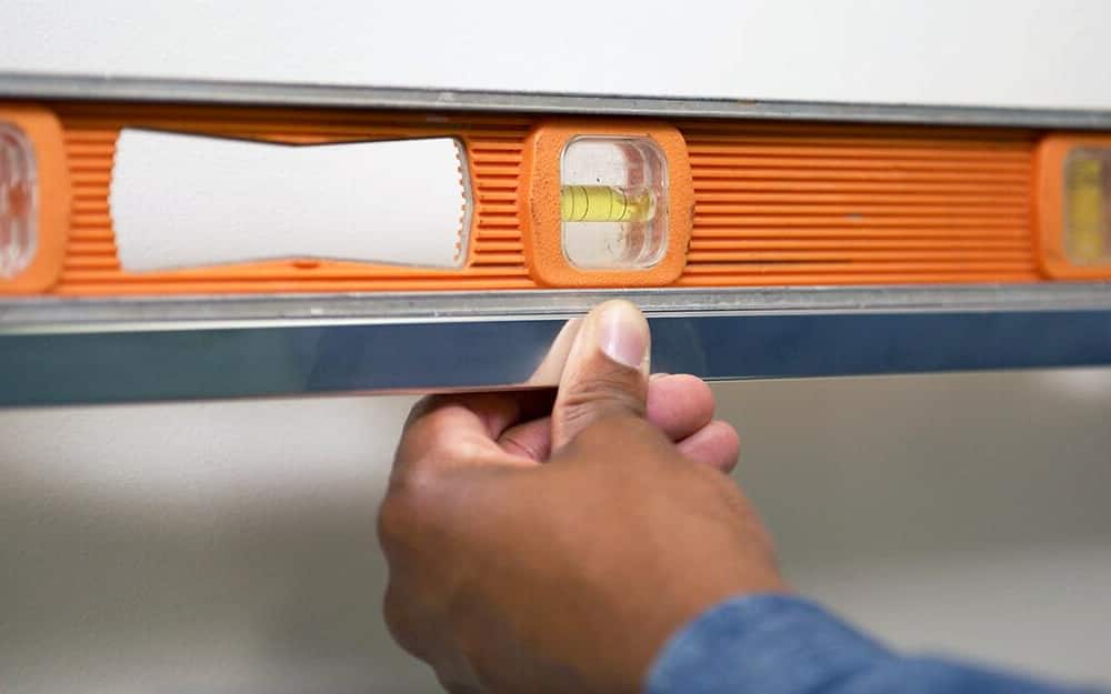 A person using a level to check measurements for a towel bar.