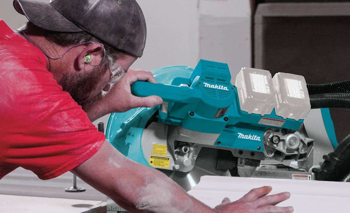 A person wears ear and eye protection while making a bevel cut using a power miter saw.