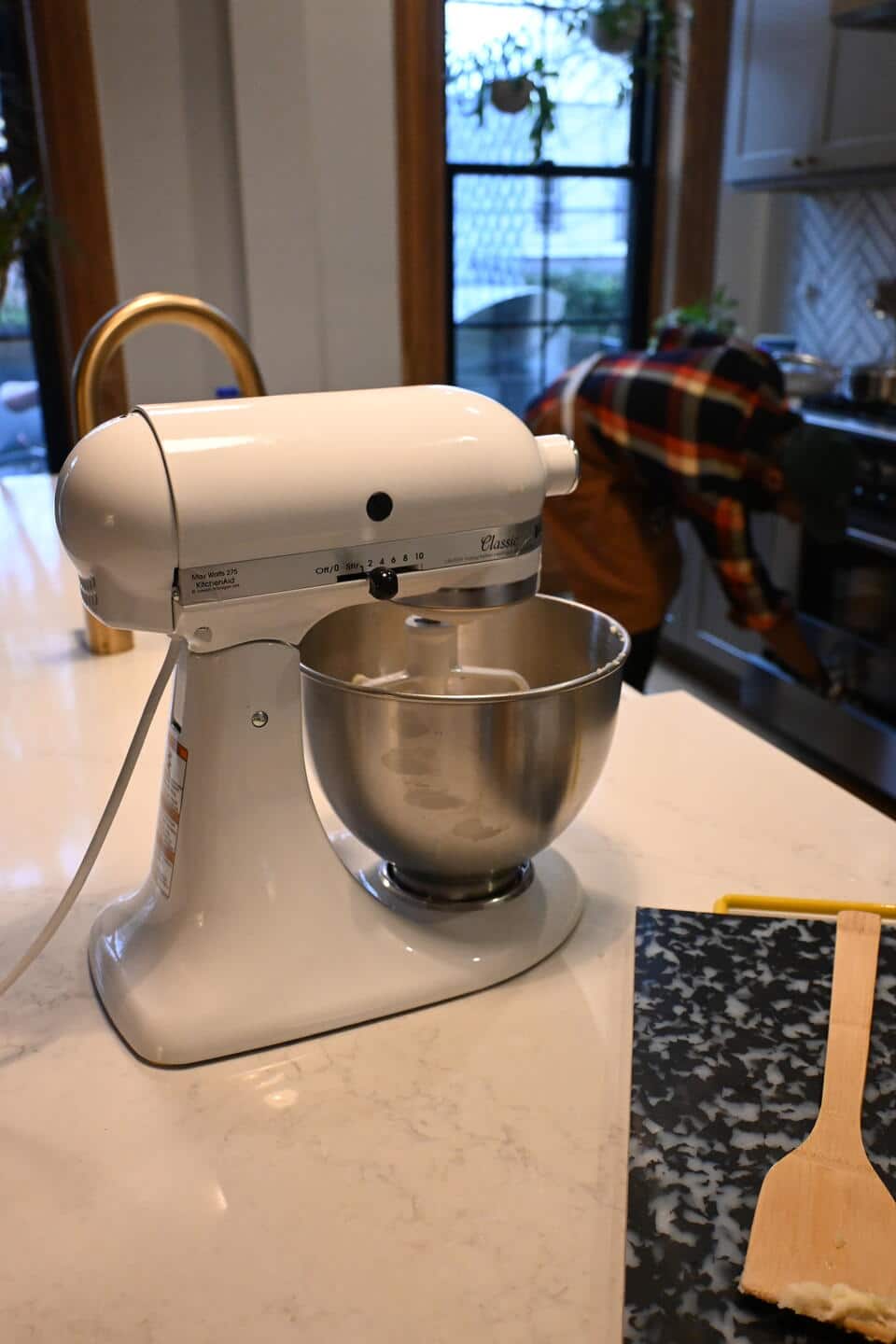 Close-up of a KitchenAid mixer with a person in the background