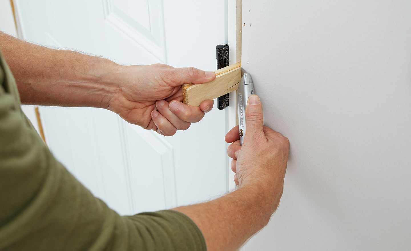 A man cut a shim while installing an exterior door.