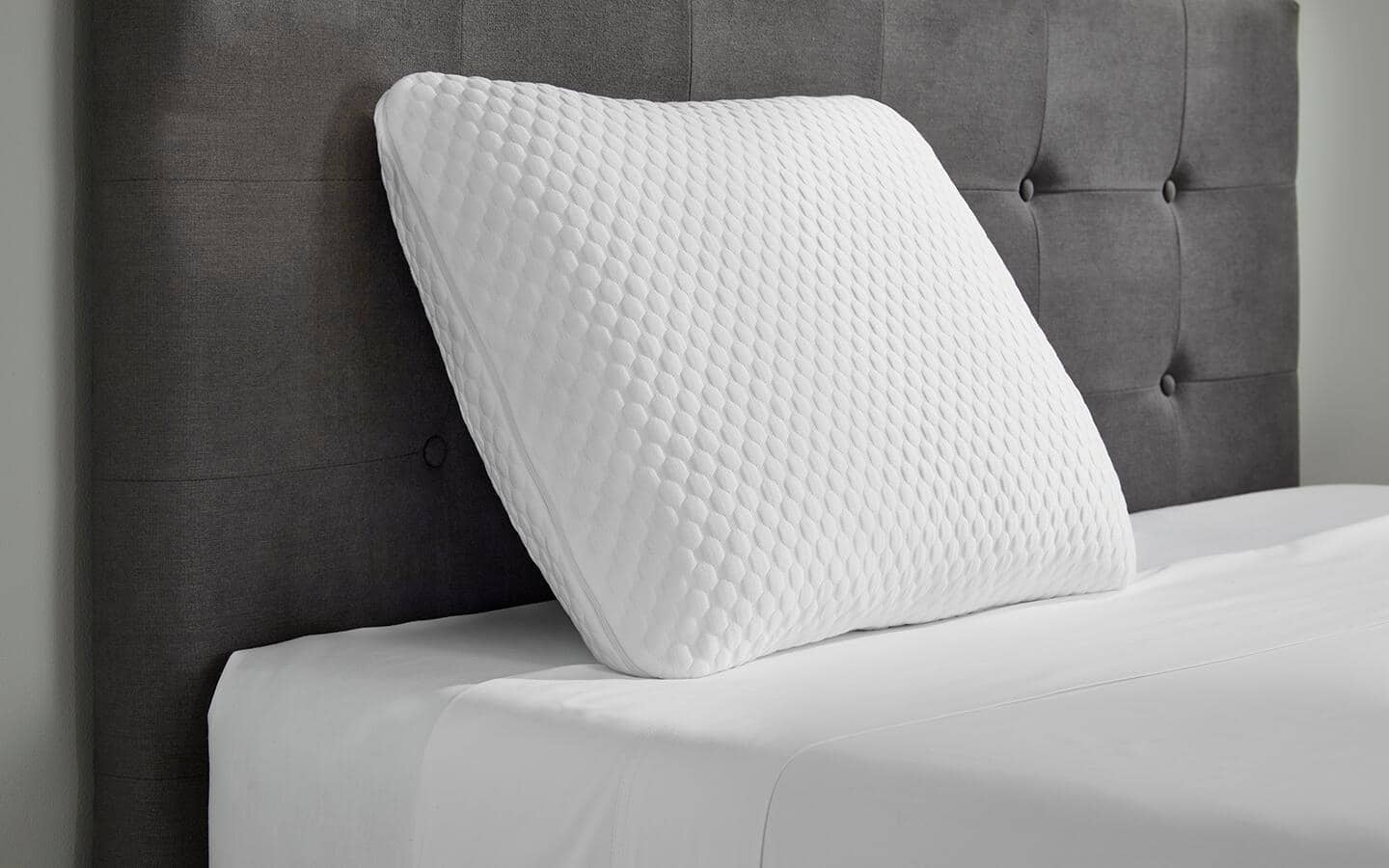 A memory foam pillow placed against a headboard. A memory foam pillow placed against a headboard.