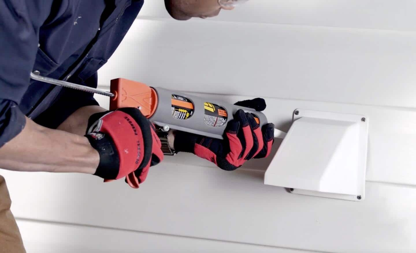 A person attaching a dryer vent on the exterior of a home.