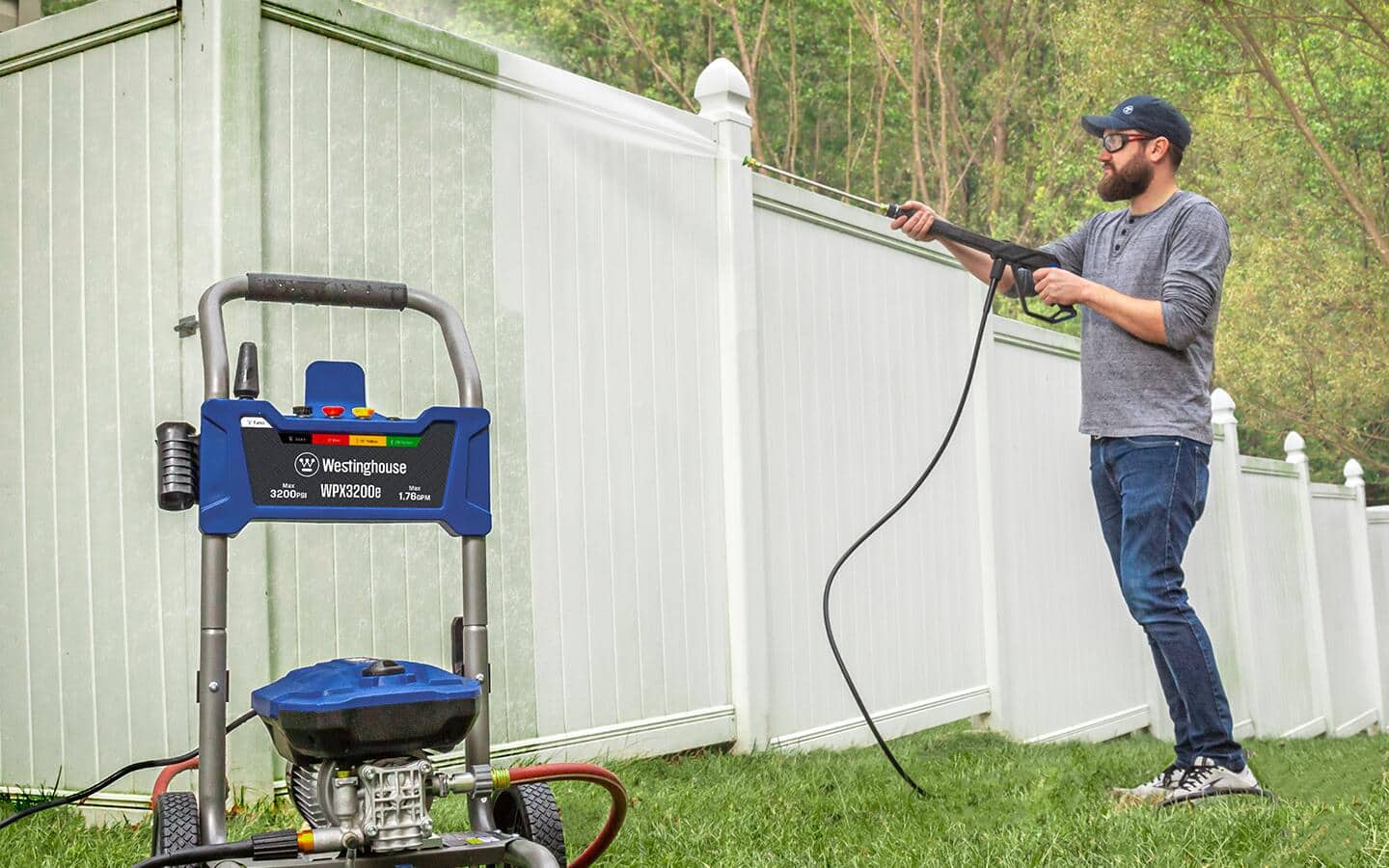 A man cleaning a vinyl fence with a pressure washer