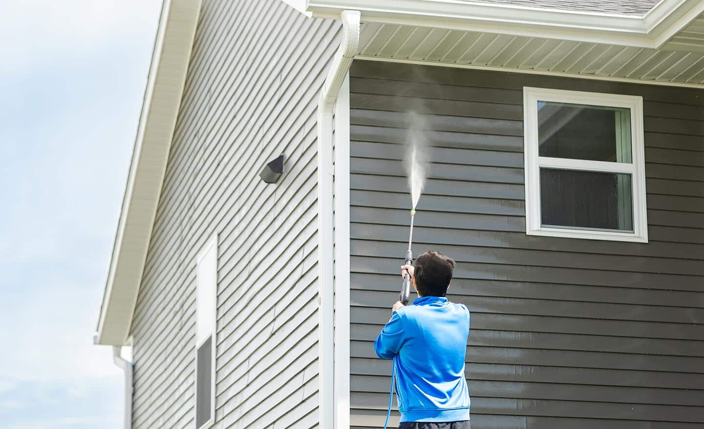 Someone pressure washing the siding on a home.