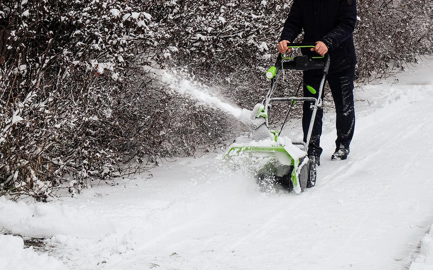 A man driving a small snow blower. A man driving a small snow blower.