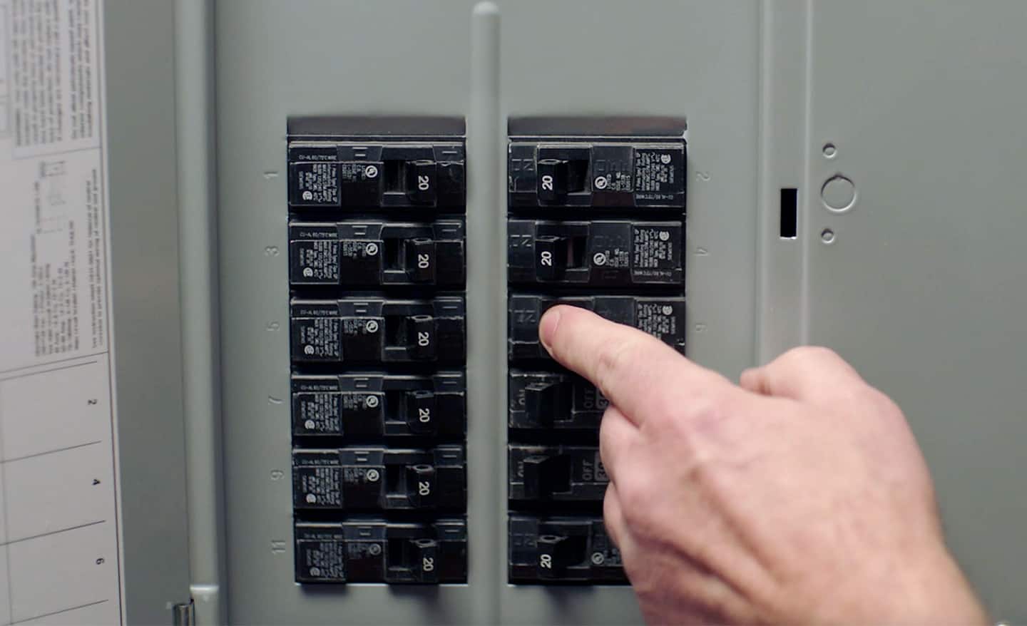 A person turns off the power to a room at a home electrical panel. 