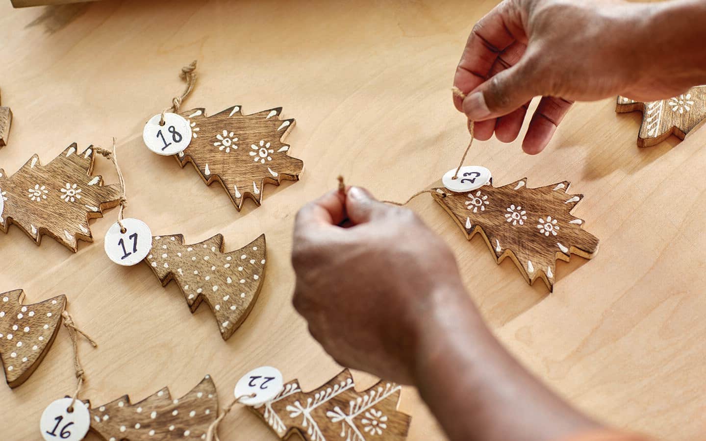 Someone tying a paper number to a wood Advent hanger.