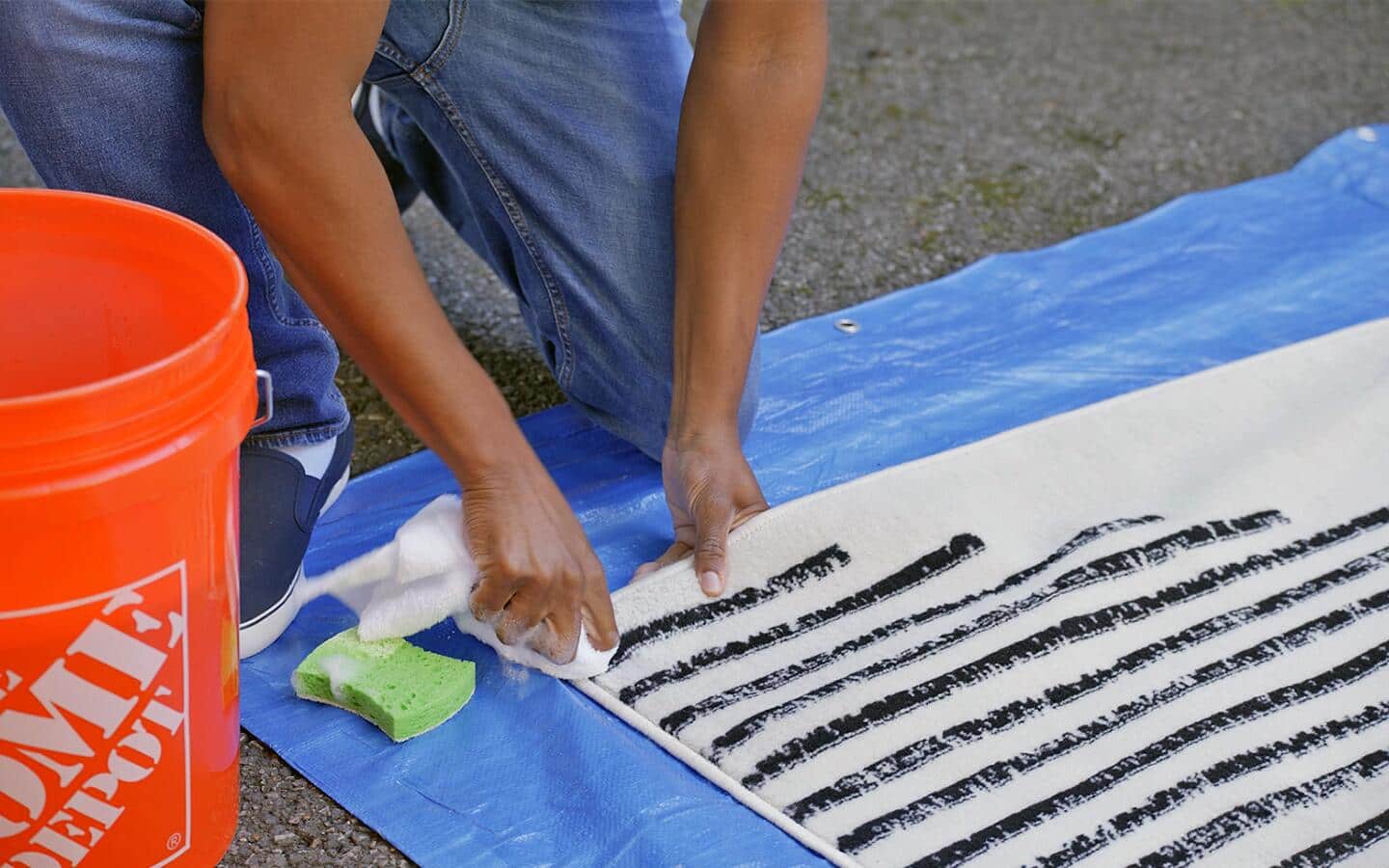 Someone applying cleaning solution to a black-and-white area rug. Someone applying cleaning solution to a black-and-white area rug.