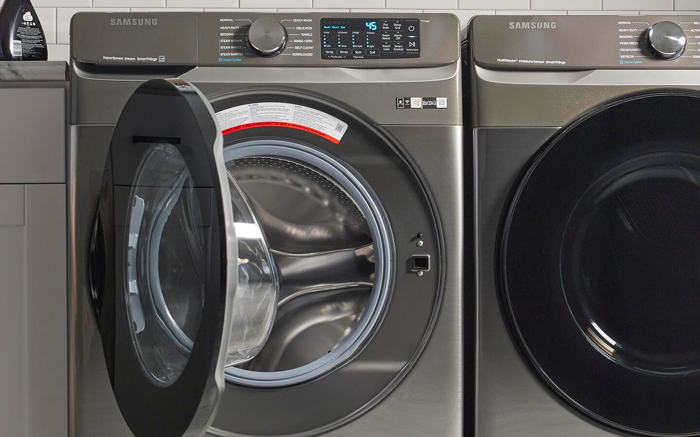 An open front-loading washing machine next to a matching dryer.