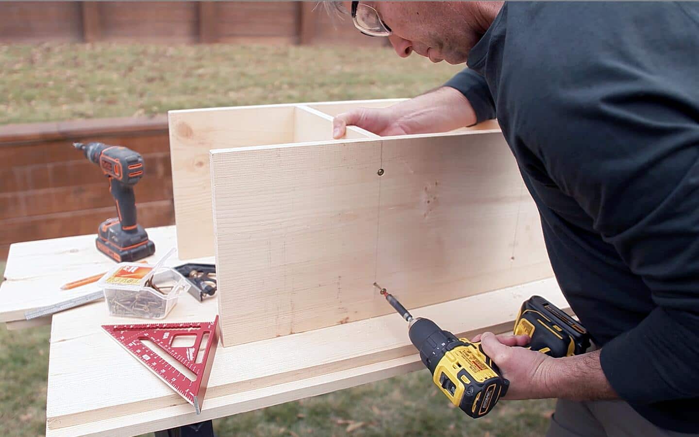 Someone drilling screws to secure the boards for a closet organizer's center section.