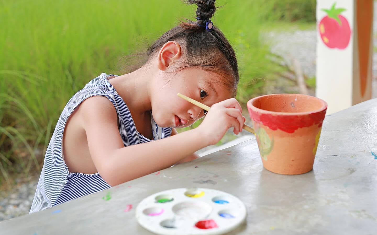 A small child paints a clay flower pot A small child paints a clay flower pot