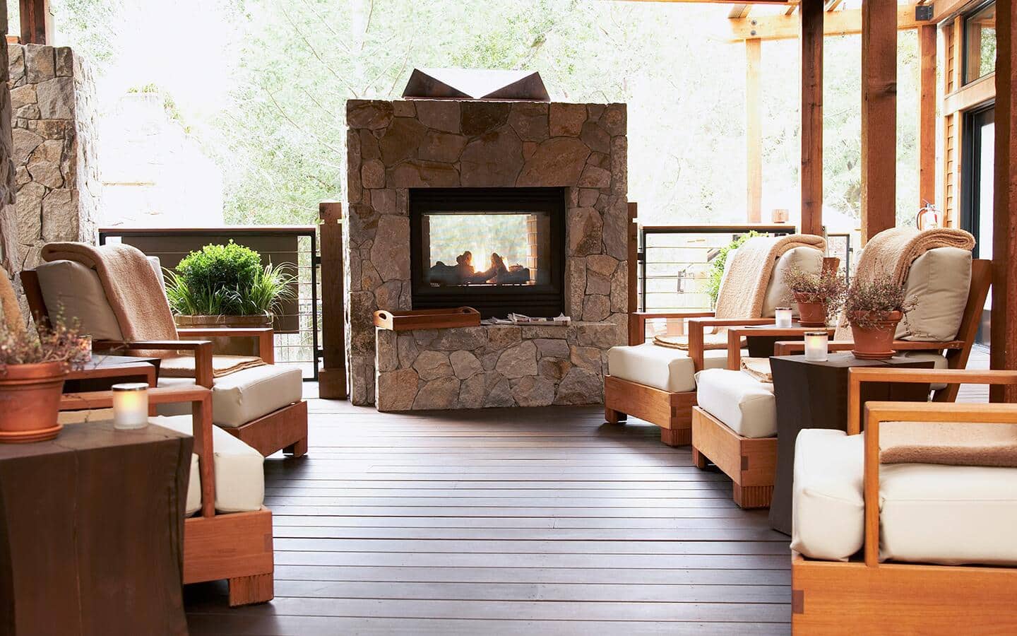 A hygge hearth surrounded by cozy, wooden patio furniture.