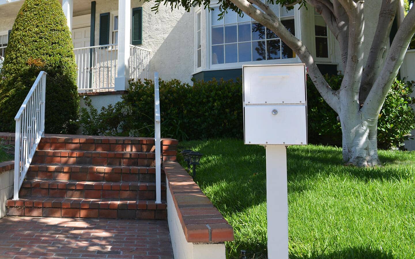 A metal mailbox installed beside the steps of a house. A metal mailbox installed beside the steps of a house.