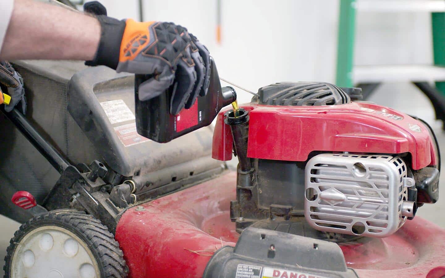 Oil is poured into a lawn mower. Oil is poured into a lawn mower.