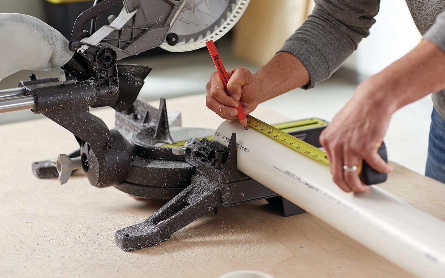 Someone measuring a PVC pipe to cut it. Someone measuring a PVC pipe to cut it.