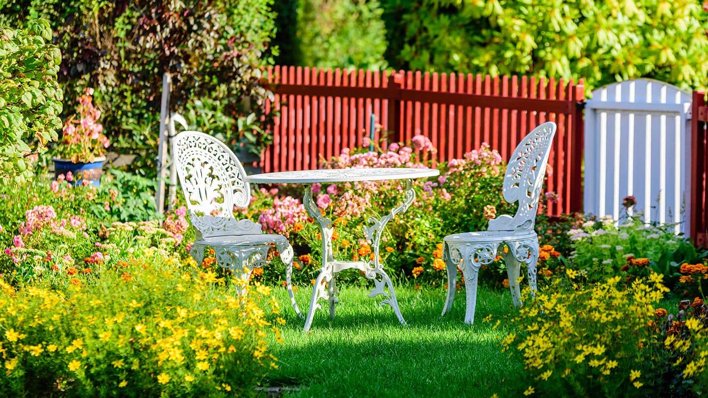 A wrought iron garden set placed in the middle of a blooming flower garden. A wrought iron garden set placed in the middle of a blooming flower garden.