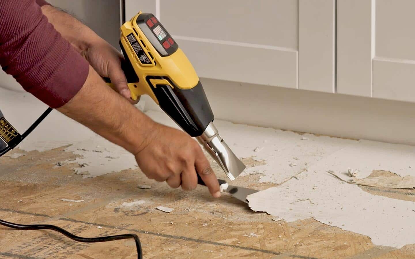 Softened flooring adhesive being scraped off with a prybar and heat gun. Softened flooring adhesive being scraped off with a prybar and heat gun.