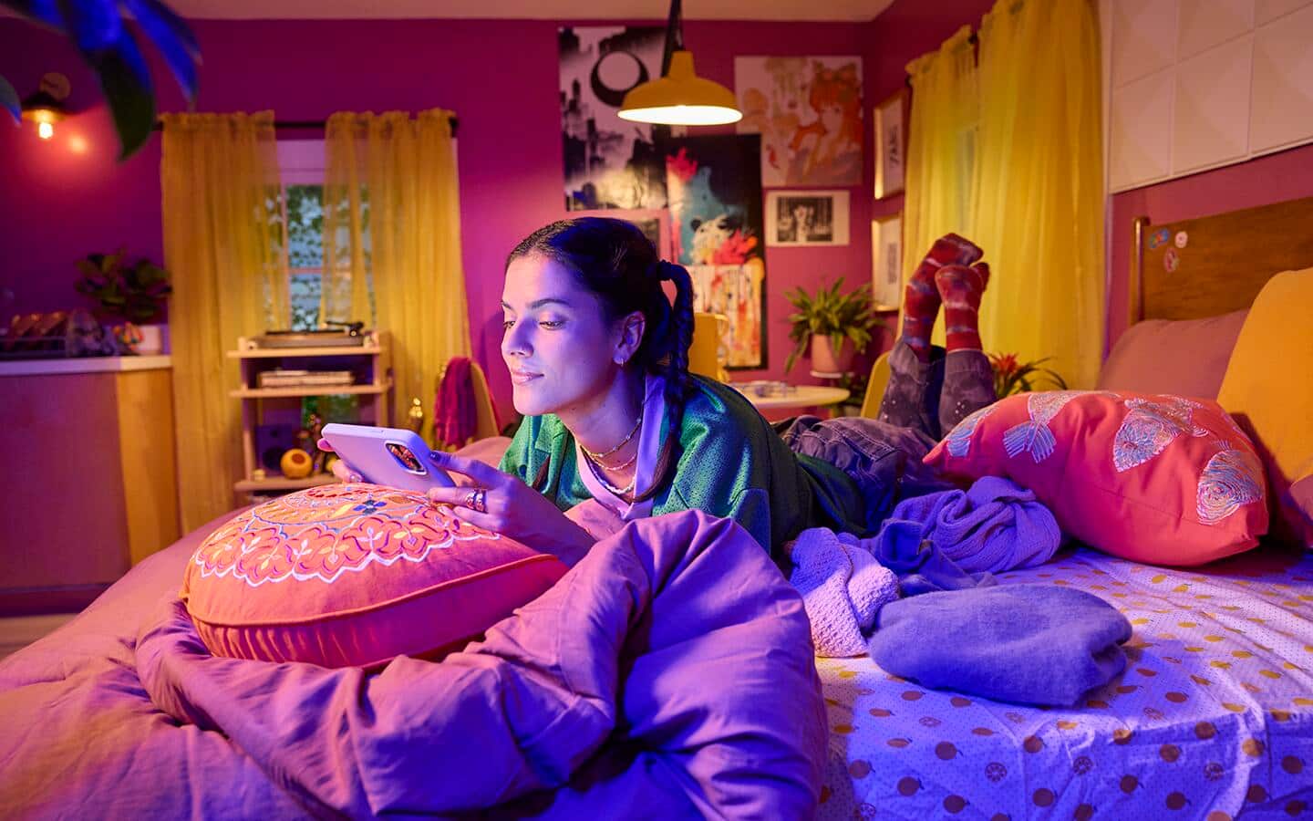 A person lying on bed holding a mobile device.