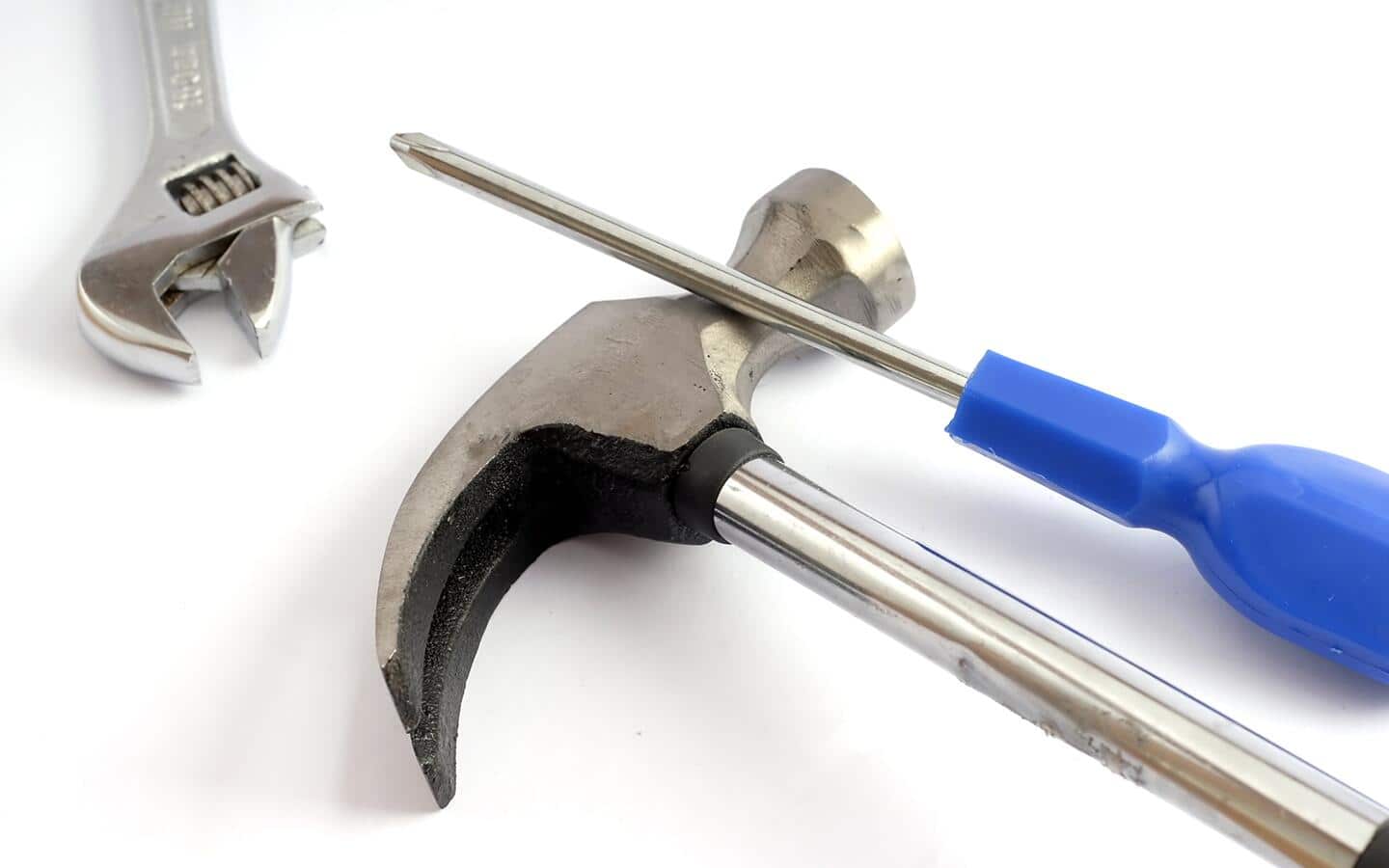 A hammer, screwdriver and wrench against a white background. A hammer, screwdriver and wrench against a white background.