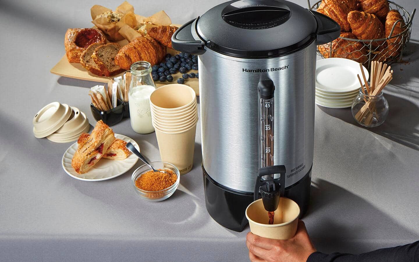 A person gets coffee from a coffee urn.