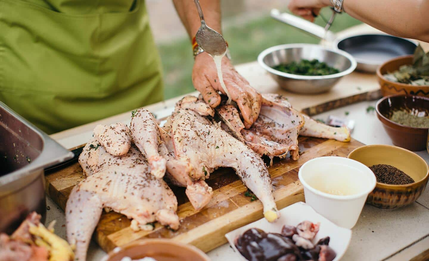 Someone setting up a grilling station with food, grilling tools and more.