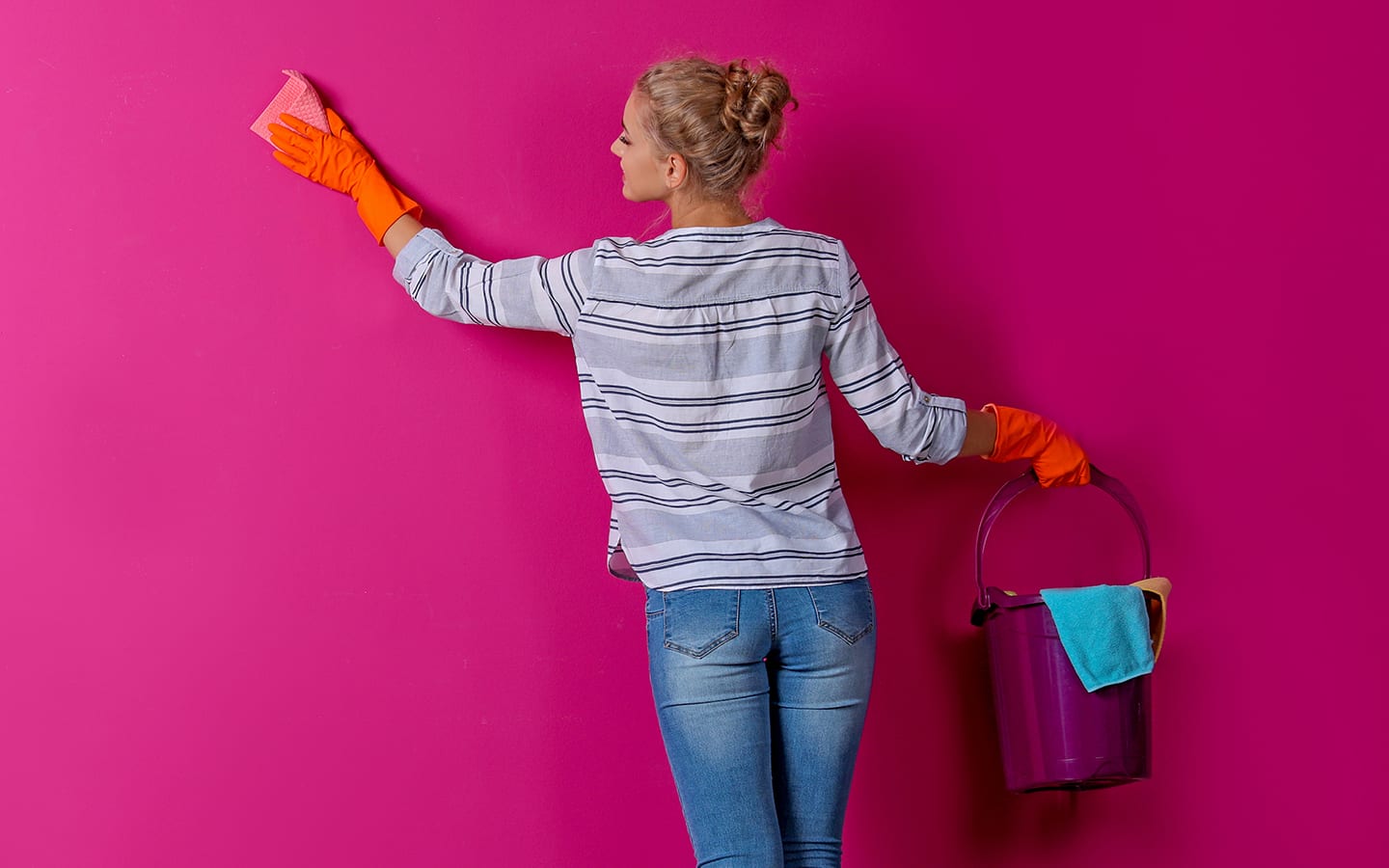 A person washes a wall with a sponge while holding a bucket. A person washes a wall with a sponge while holding a bucket.