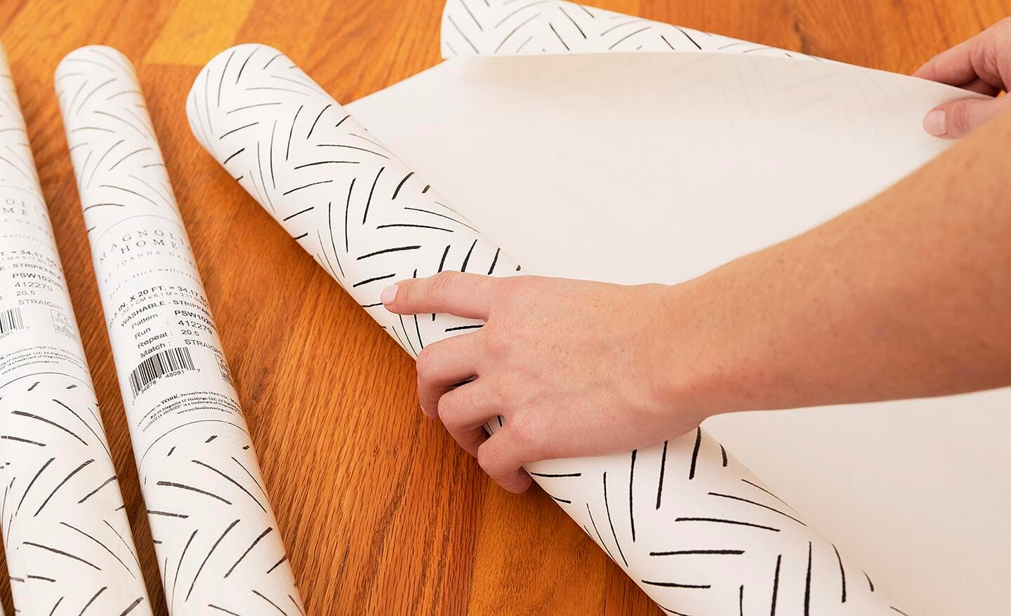 Someone rolling out wallpaper to measure and cut.
