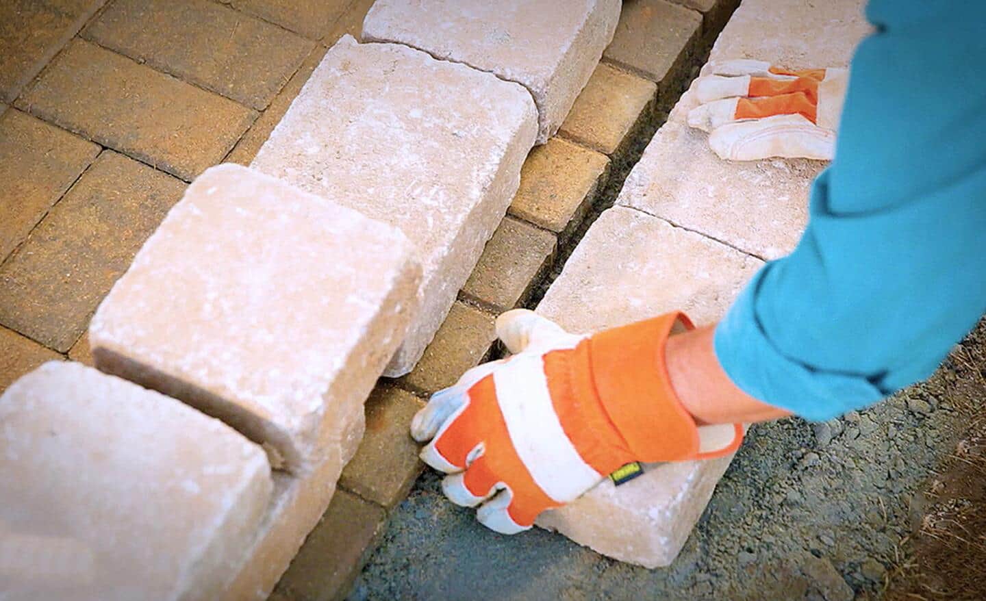 A person laying the first course of retaining wall blocks.