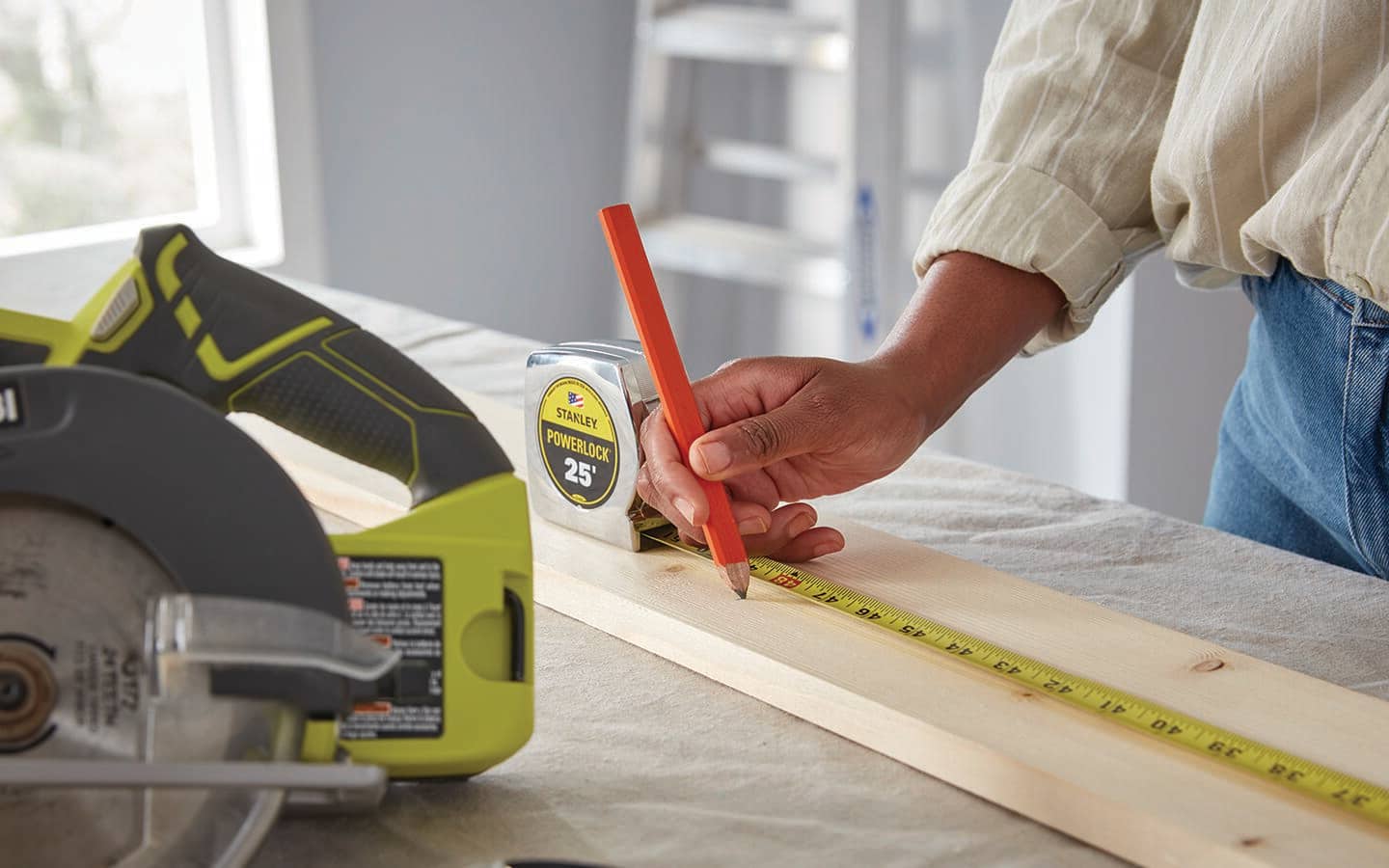 A person measures and marks a piece of wood.
