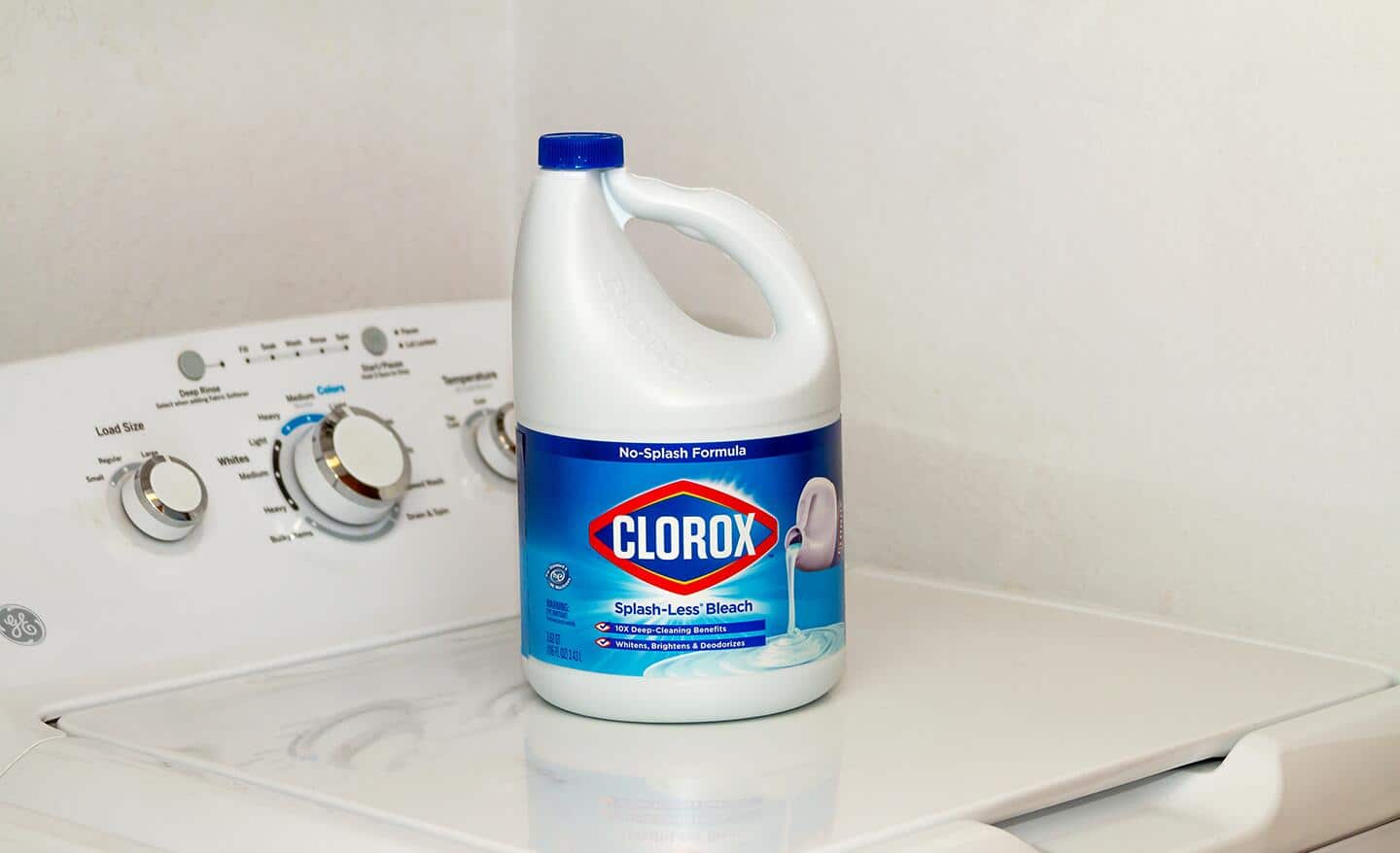 A bottle of bleach sitting on top of a washing machine.