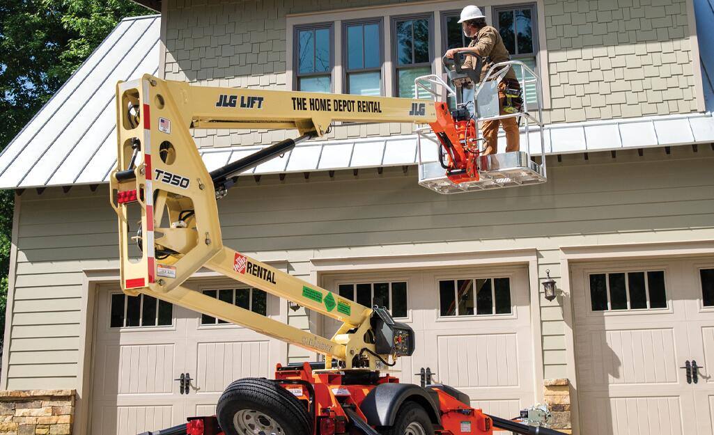 A Pro operates a boom lift outside a house. A Pro operates a boom lift outside a house.