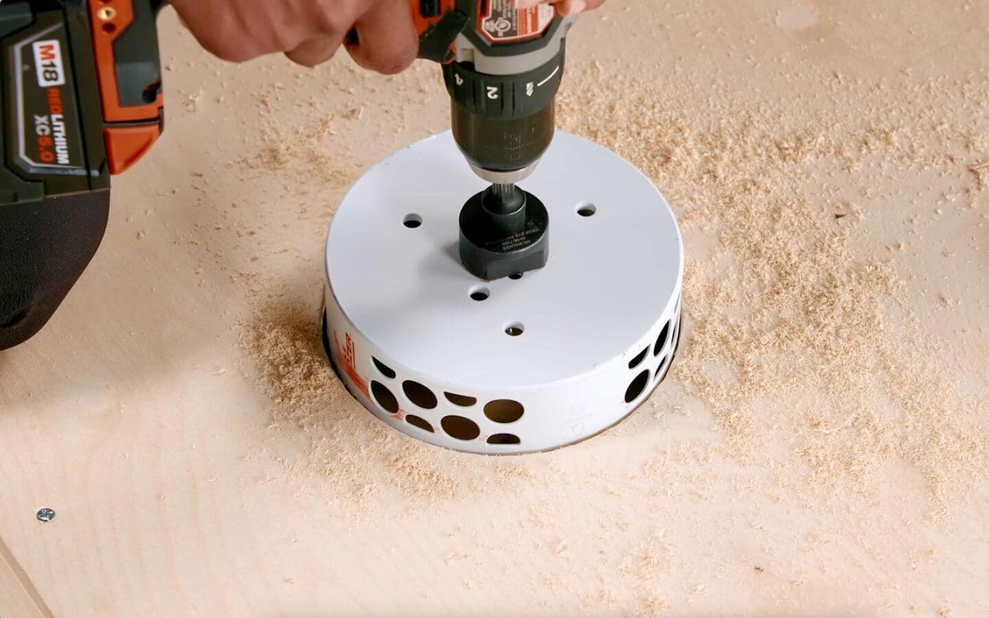 Someone using a 6-inch saw to drill a hole into plywood. Someone using a 6-inch saw to drill a hole into plywood.